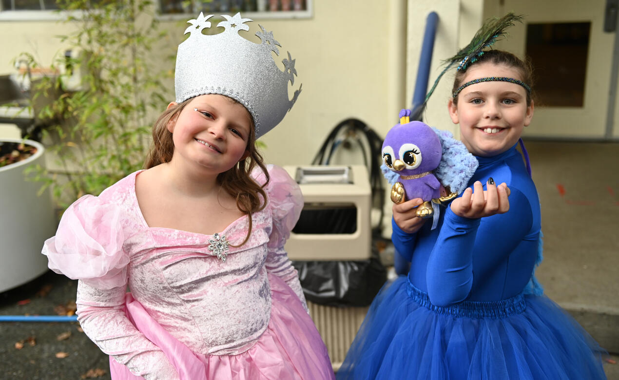 Two students dressed in colourful Halloween gowns smile for a photo