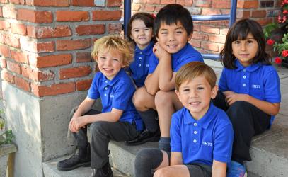 Junior Kindergarten students sitting on the front steps of the school