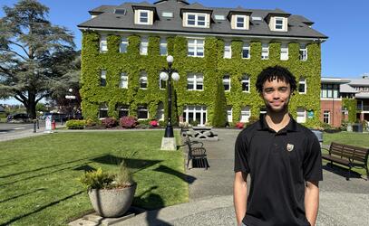 Grade 12 student Joh'nell Cleveland Junior stands for a photo in the SMUS quad with the Schoolhouse ivy in the background