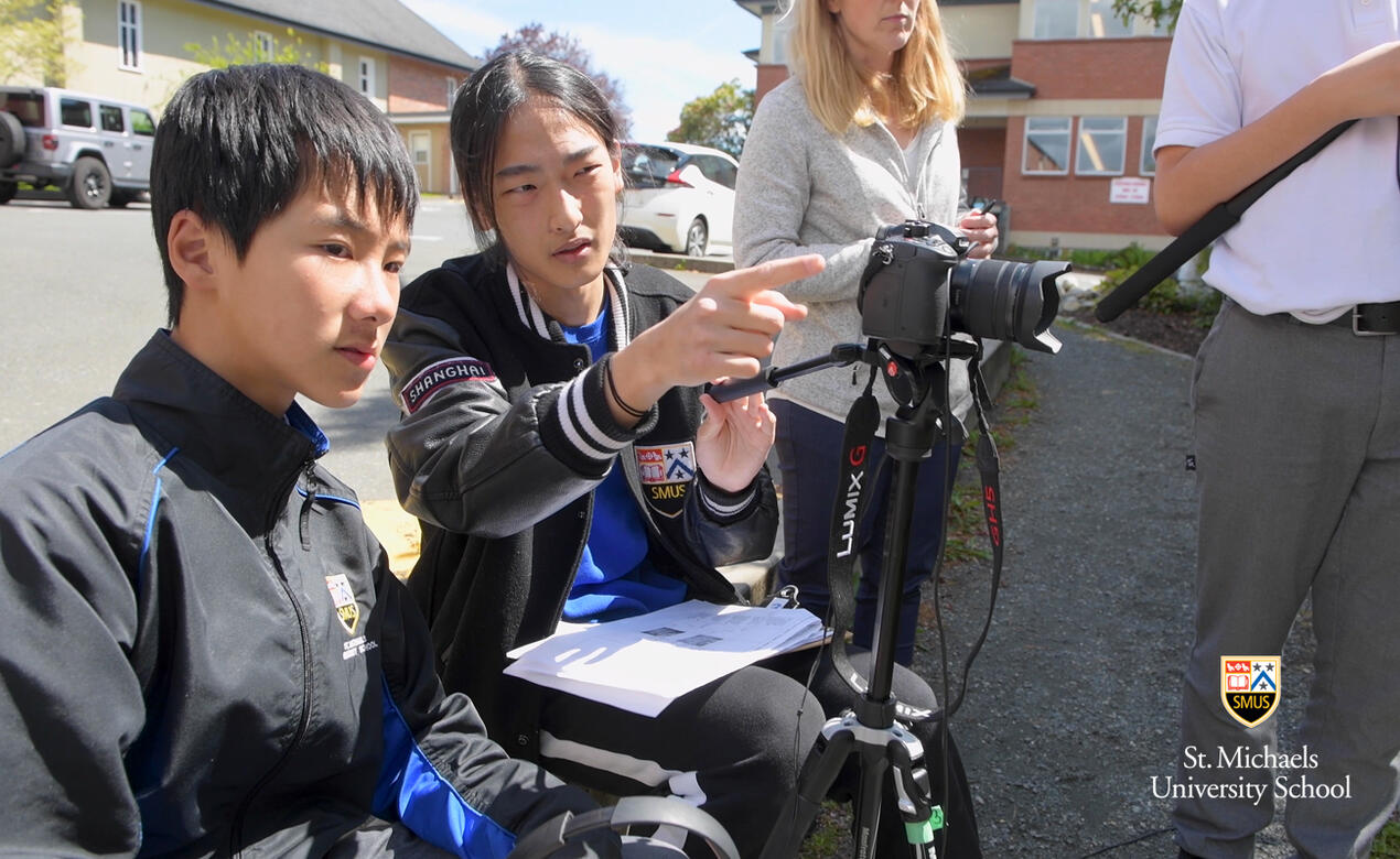Grade 11 student filmmaker Steven Song works with a Grade 8 student behind the scenes on The 50 Year Curse movie
