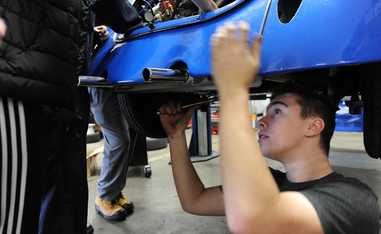 Experiential student doing mechanical work on a car