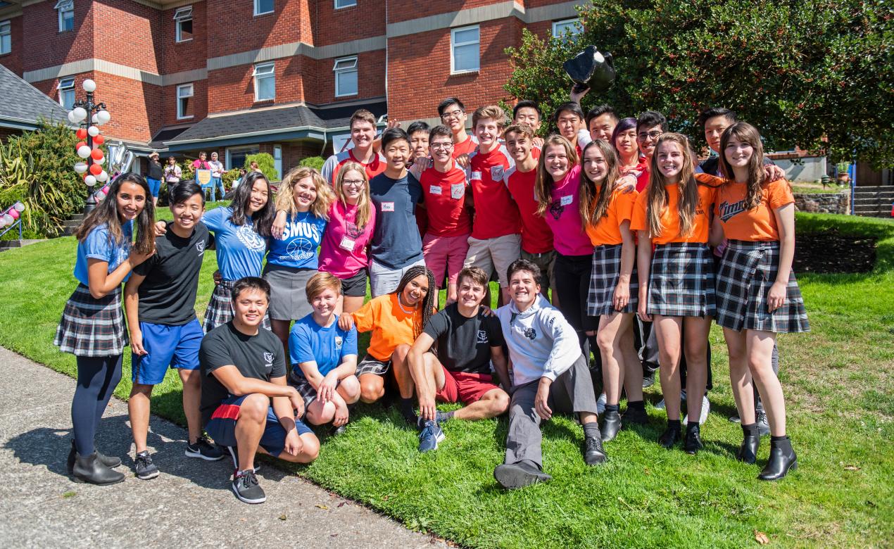 Large group of boarding students in their house shirts in front of houses