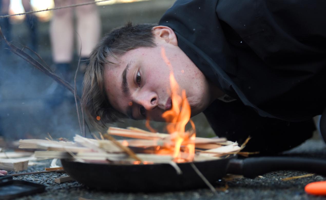 A student makes fire during an outdoor education survival skills lesson.