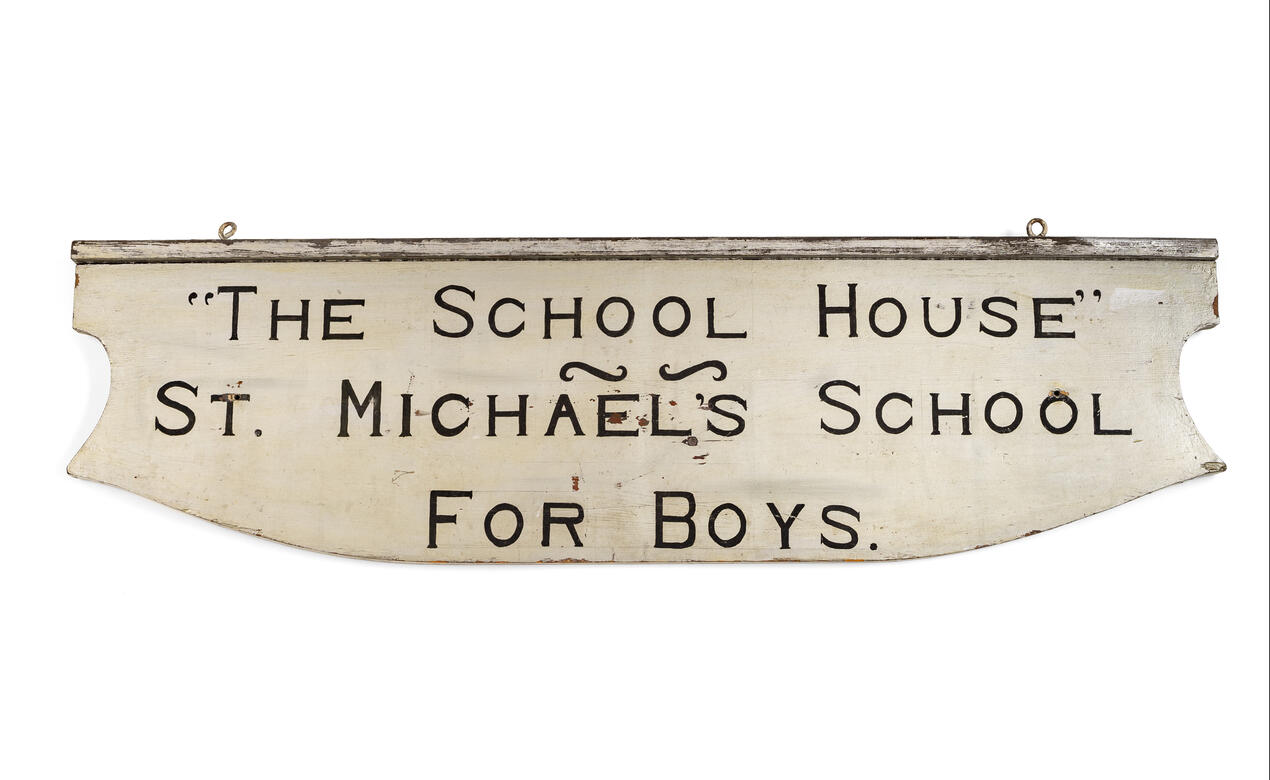 An old, white sign that reads "The School House - St. Michael's School for Boys".
