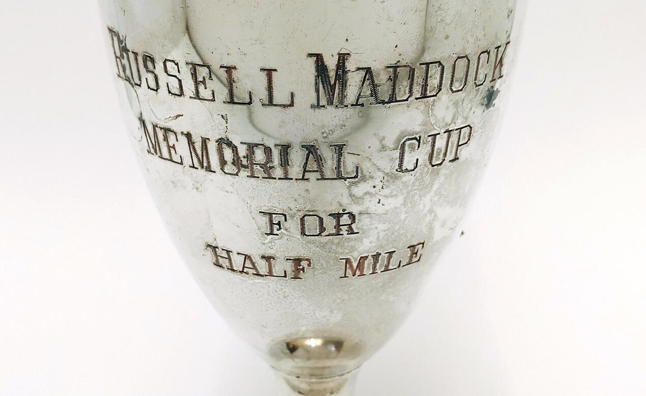 A detail of an old trophy that reads Russell Maddock Memorial Cup for Half Mile