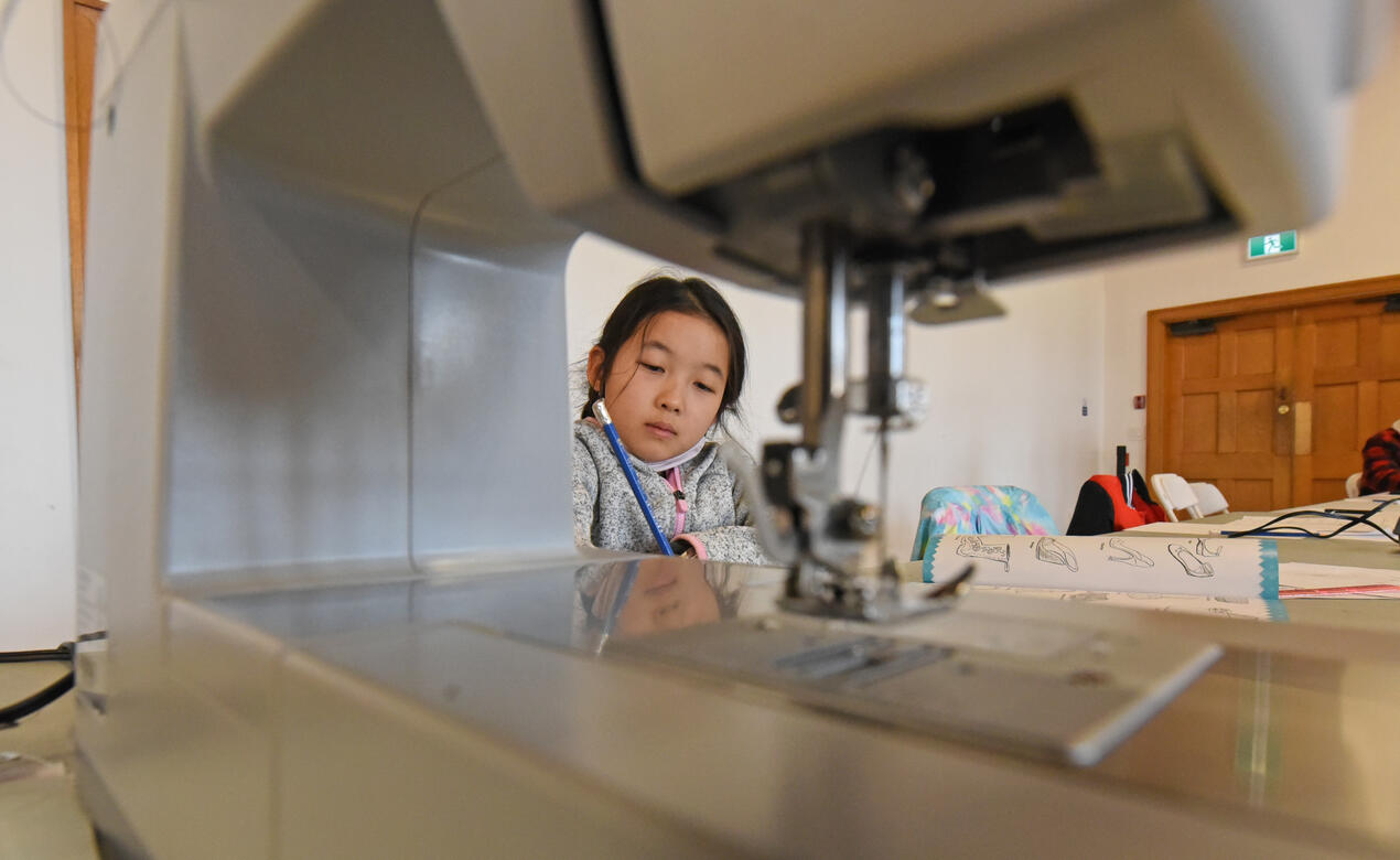 A student in the fashion design spring break camp is framed by a sewing machine.