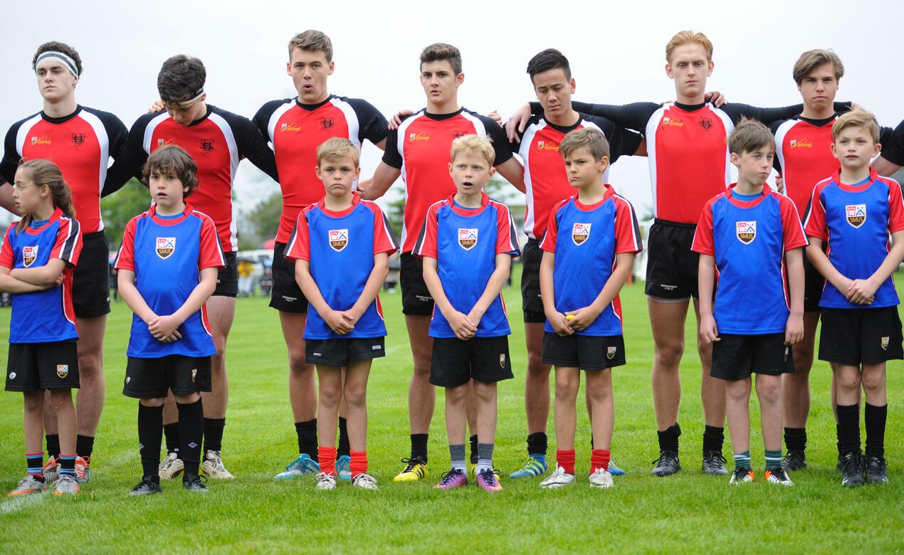 Junior School students stand in front of Senior School rugby players ahead of a game.