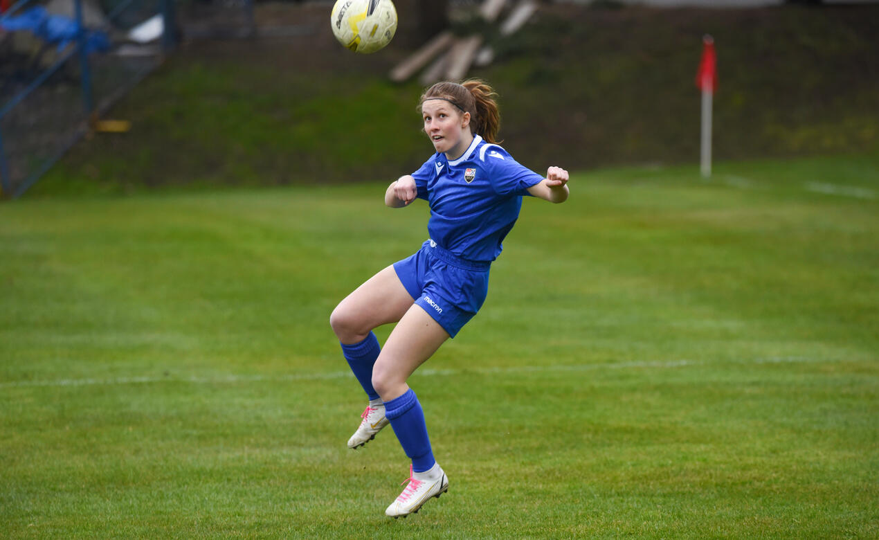 A student athlete jumps in the air to head the soccer ball