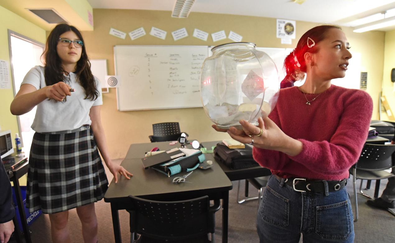 Alumna Ann Makosinski holds up a fishbowl as a Grade 8 student shines a laser through it