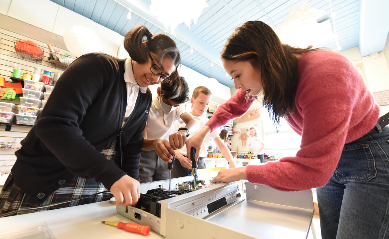 Alumna Ann Makosinski '15 works alongside a Junior School student using tools to take apart an old VCR/DVD player in the Imagination Lab