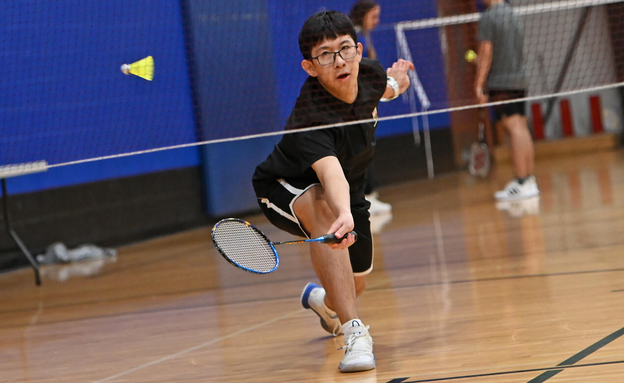 A badminton player reaches to hit the birdie