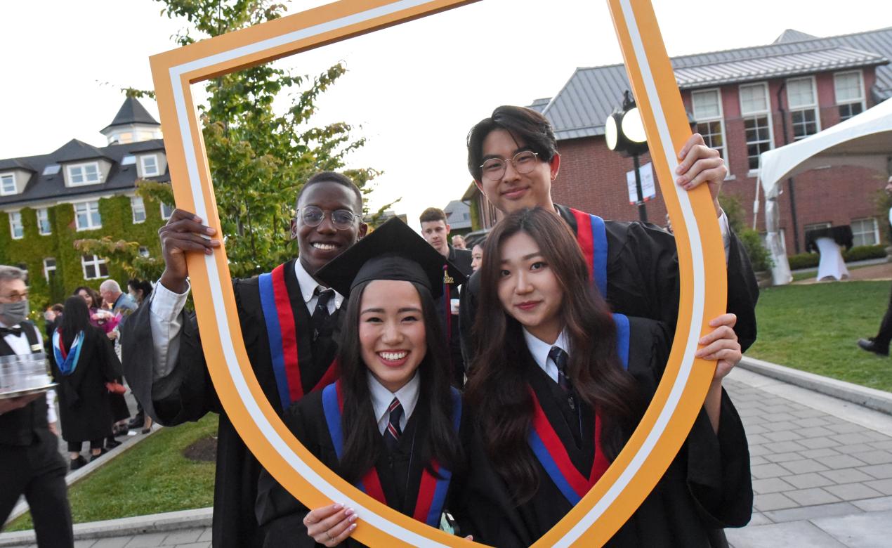 A group of Grade 12 students pose with the SMUS crest after graduation