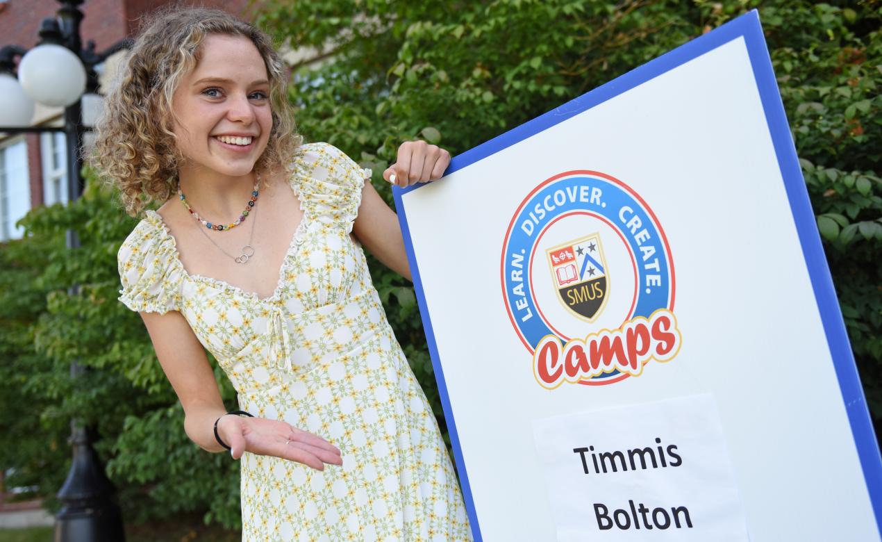 Aysha Emmerson '18 poses with a Timmis Bolton sign 