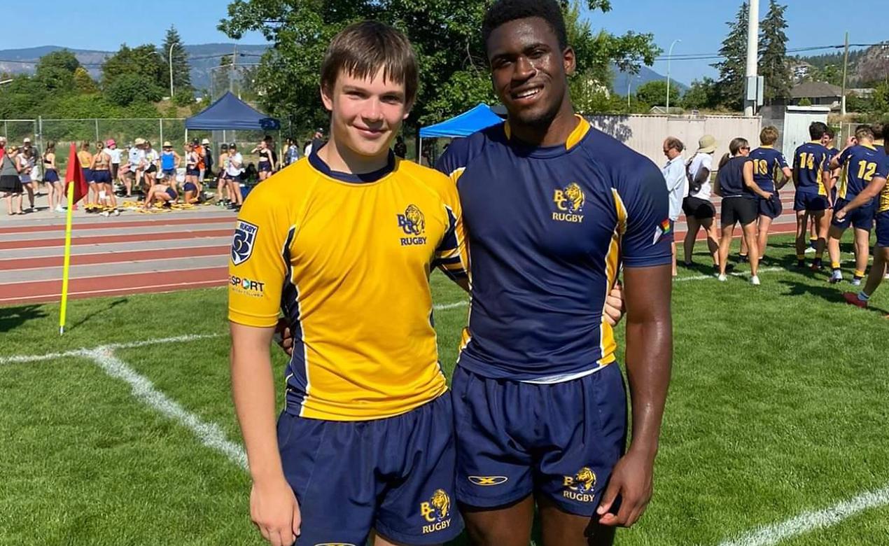 Two rugby athletes, Carter Haddow and Dave Duru, pose on the rugby pitch