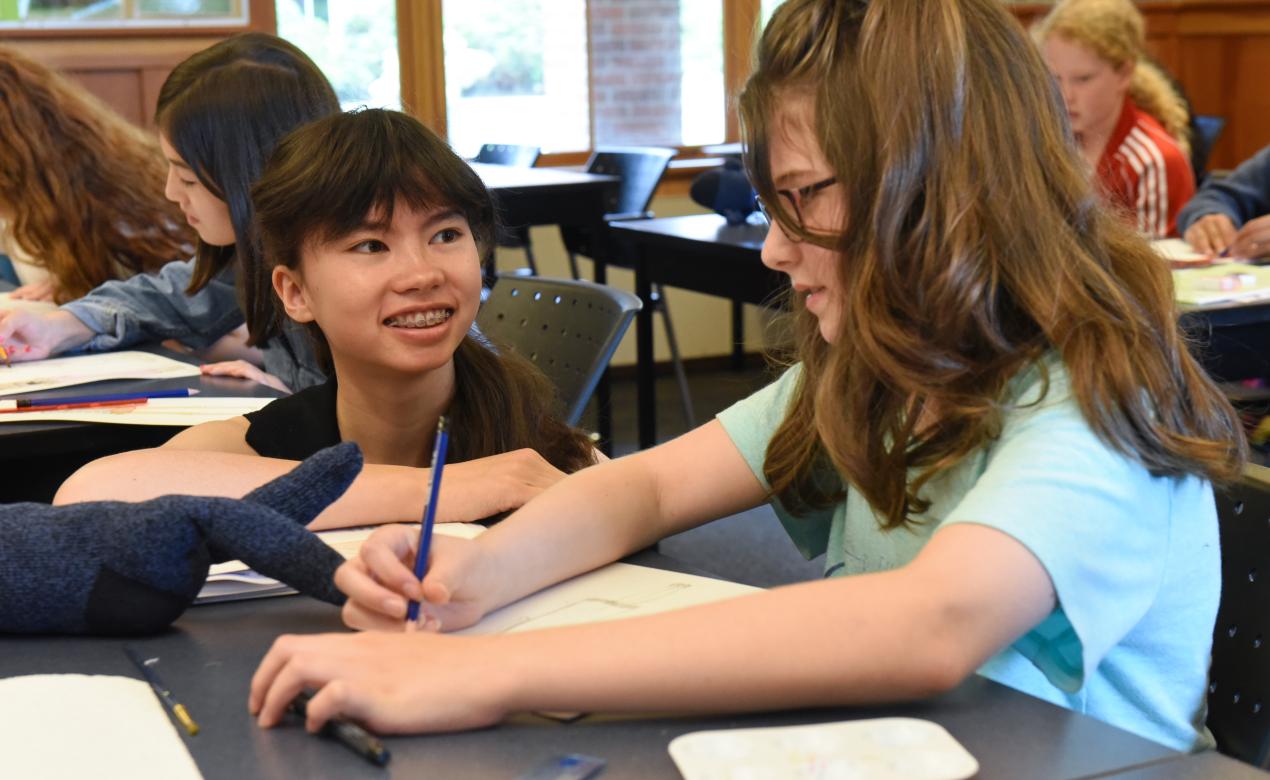 Camp assistant Zoe works alongside a student in the fashion design and sewing camp.