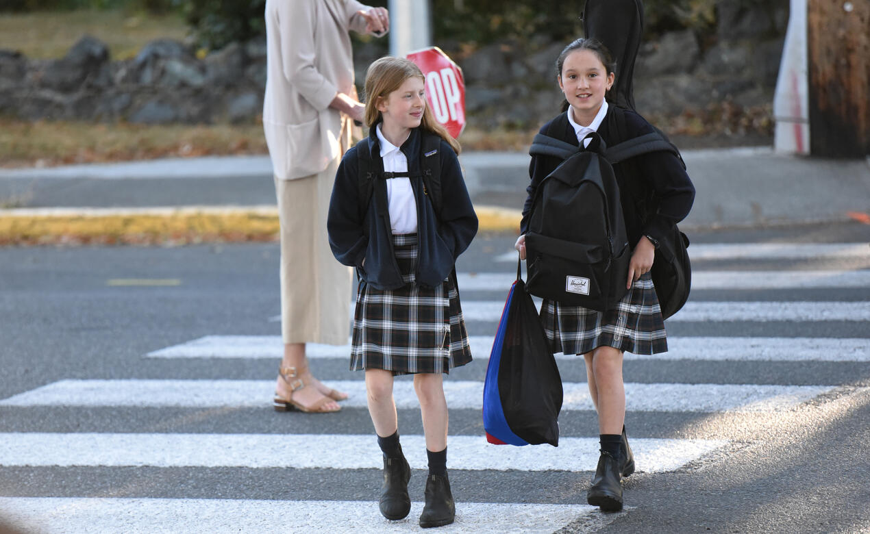 Two Junior School students walk across a crosswalk in conversation