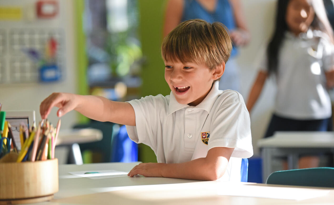 A Grade 2 student smiles at their desk on the first day at the Junior School.