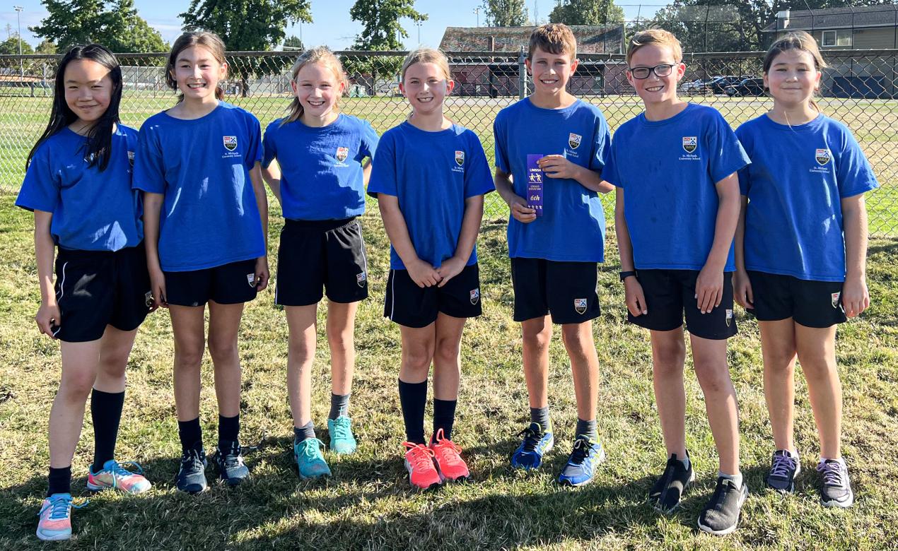 A group of seven Middle School cross country athletes pose together after a race