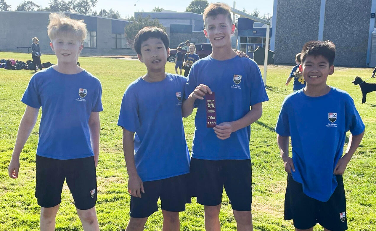 A group of four Middle School cross country athletes pose together after a race