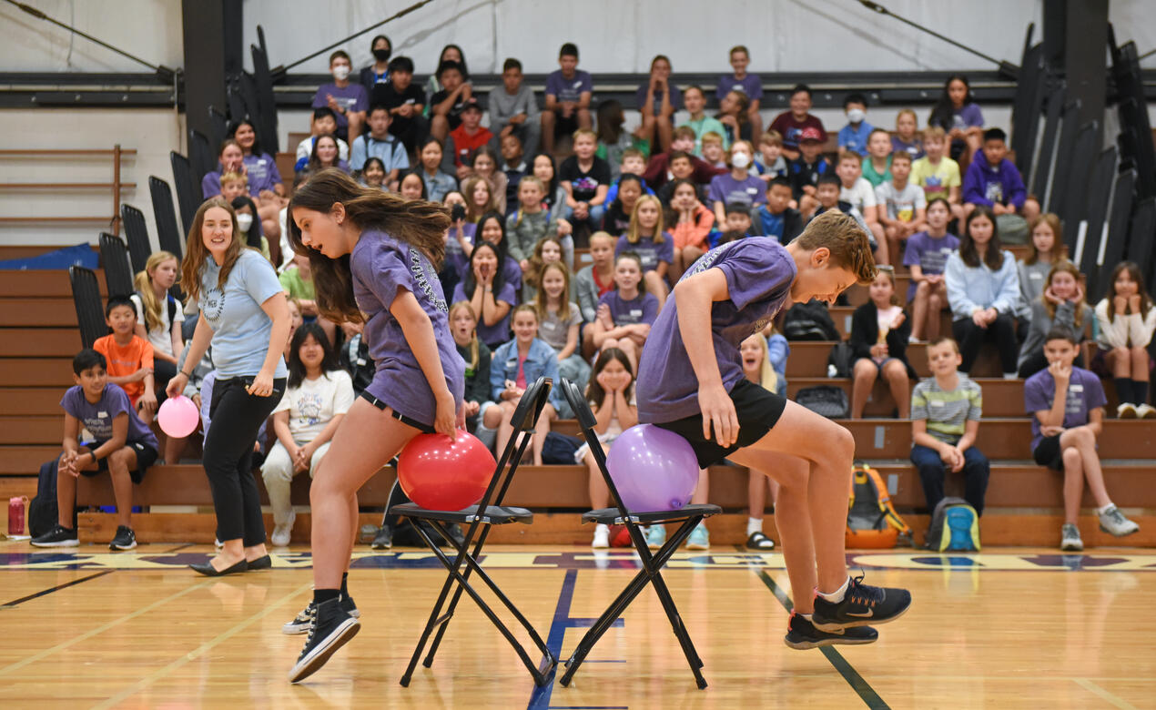 Middle School WEB Leaders jump in the air to try and pop balloons against a chair