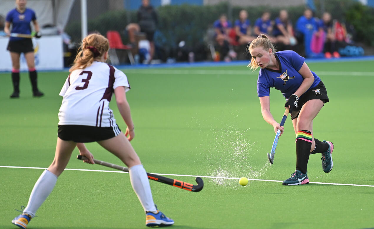 A SMUS field hockey player hits the ball.