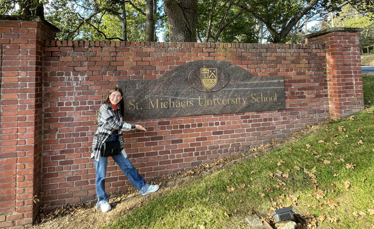 A student poses and smiles for a photo in front of the SMUS sign