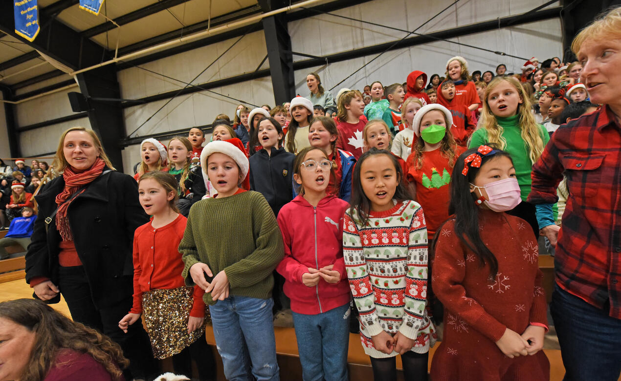 A group of students wearing colourful Christmas clothing sing The 12 Days of Christmas