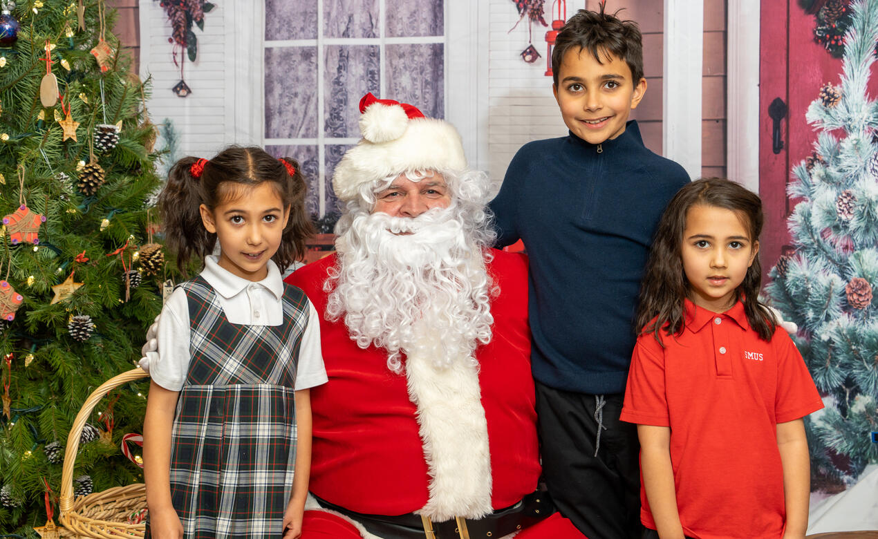 A trio of students pose for a photo with Santa