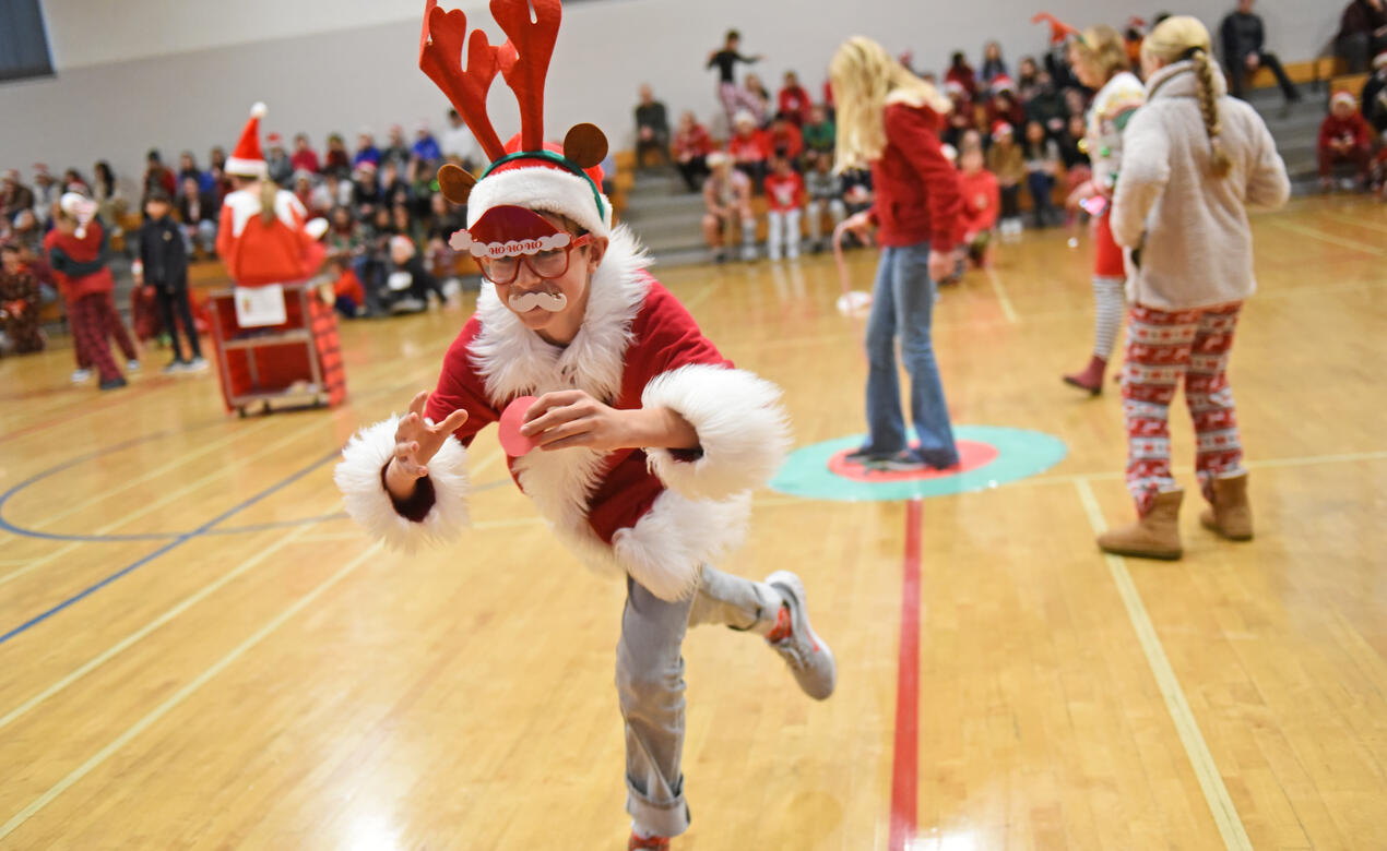 A student dressed in a Christmas costume runs in the gym during Middle School Reindeer Games