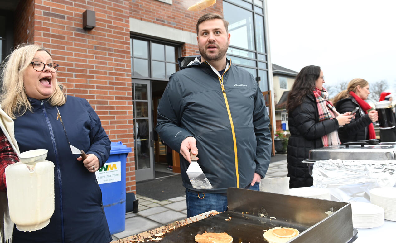 Mr. Dave Heffernan flips a pancake while Ms. Carole McMillan watches in awe