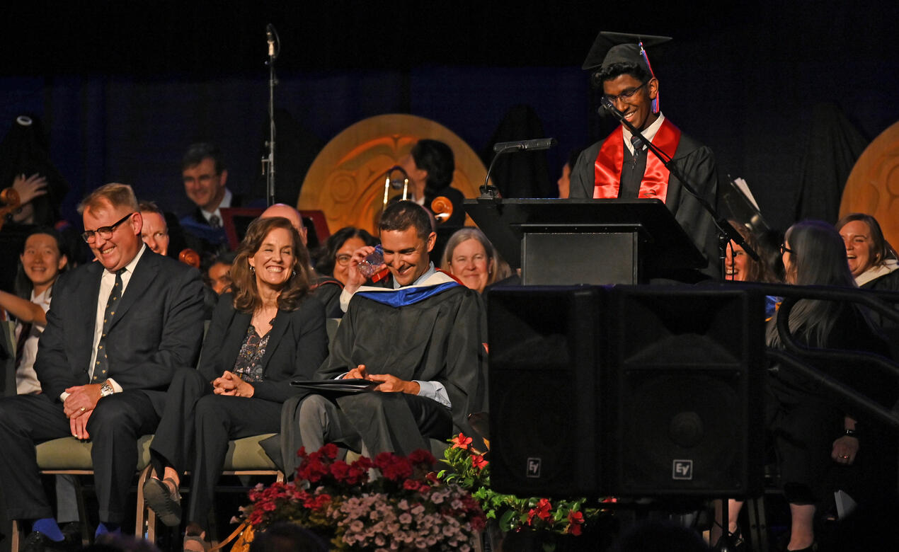 Faculty and guests laugh at a joke during the valedictory speech