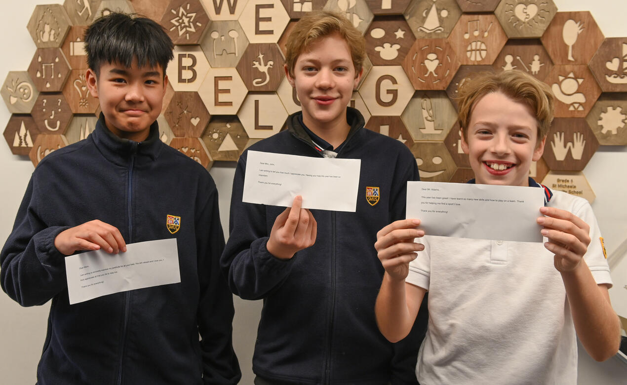 3 students hold up notes of gratitude