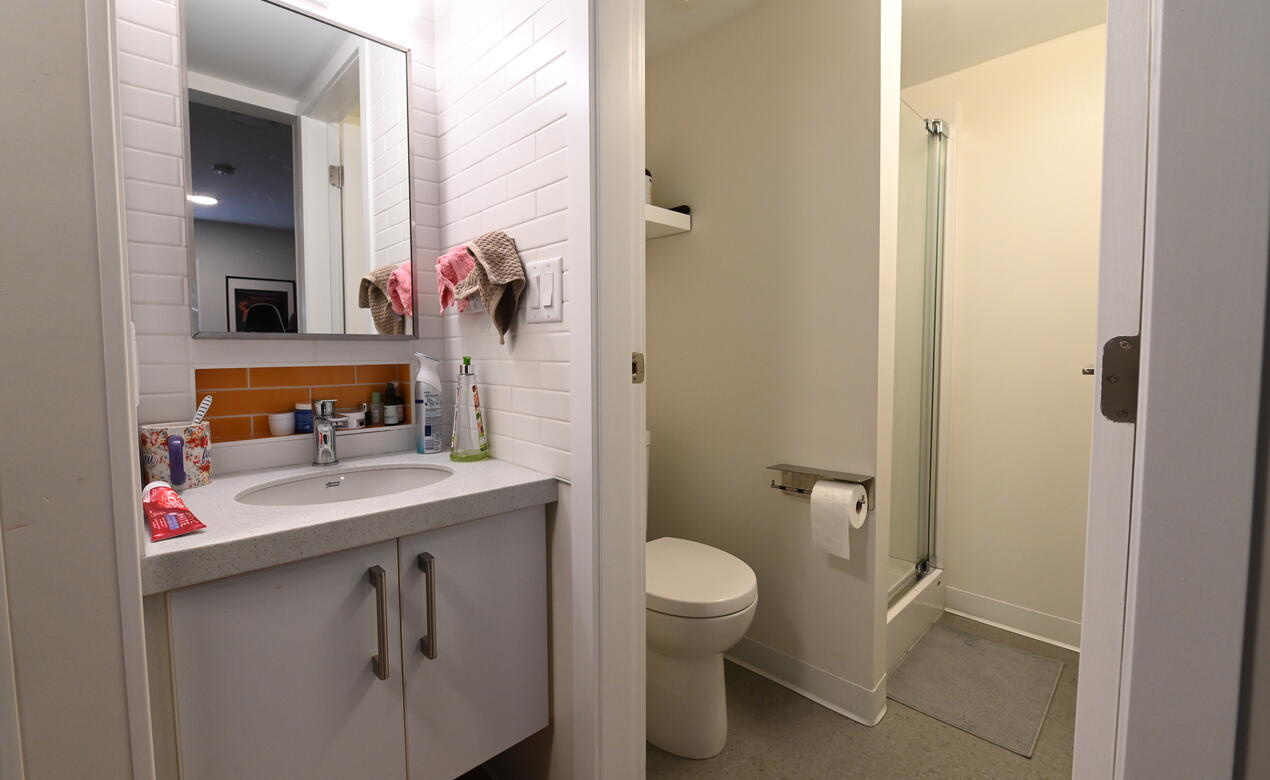 A bathroom sink, storage, toilet and shower are in each room