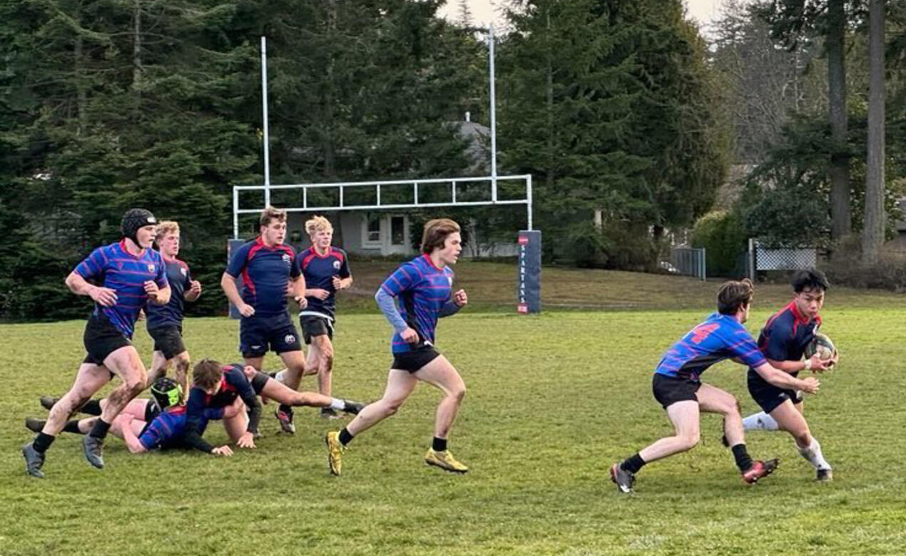 A student tackles an opposing player as others run on