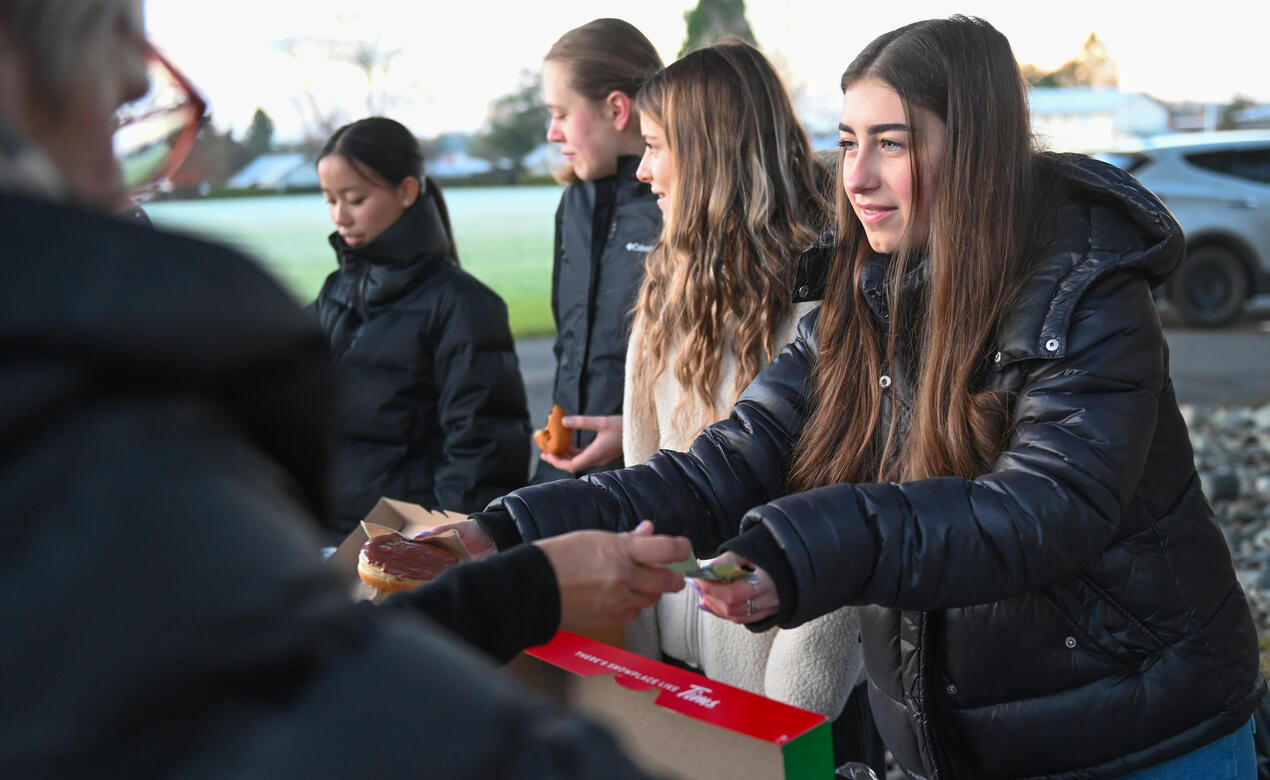 Ilone serves customers donuts and coffee at a fundraiser event