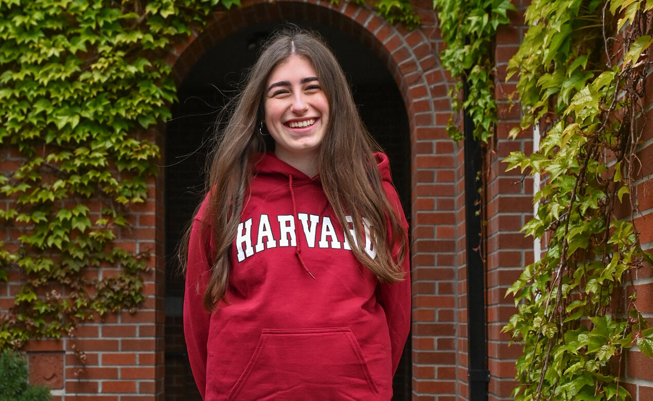 Ilona smiles whilst wearing her Harvard hoodie
