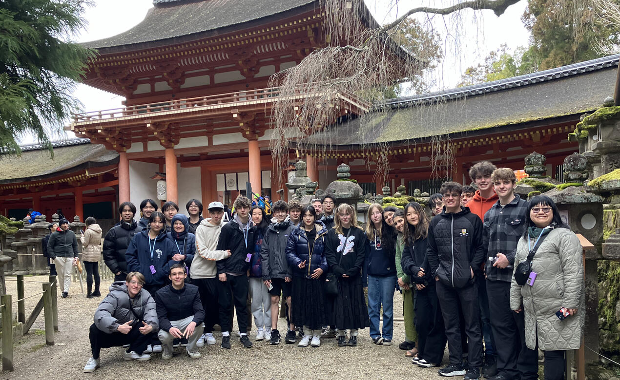 The group stands in front of a beautiful Japanese building