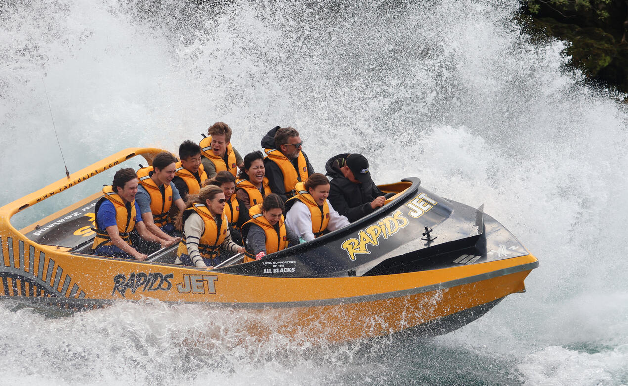 Students hang on tightly as their jetboat crashes through a wave