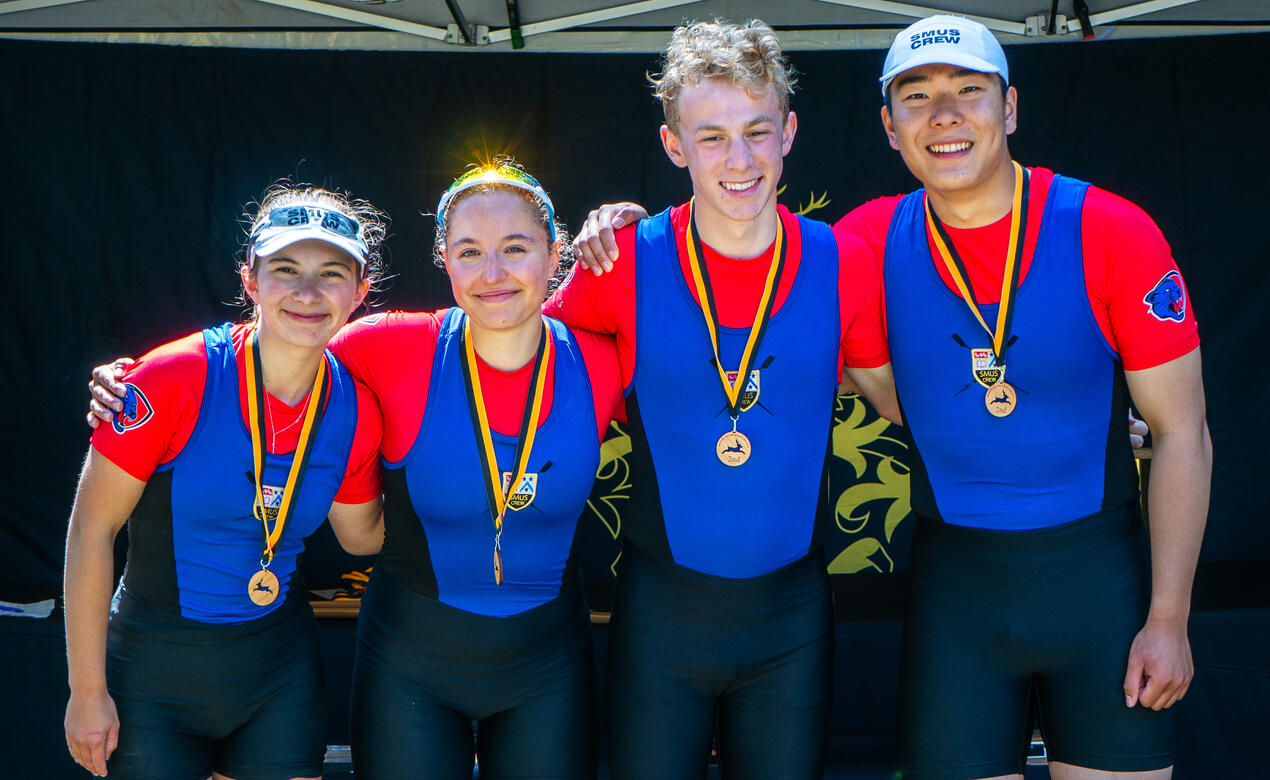 Four rowers stand on the stage with their medals