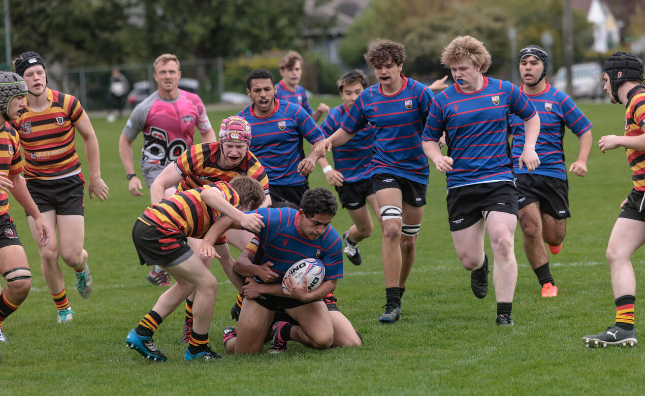 Players support their teammate who is being tackled