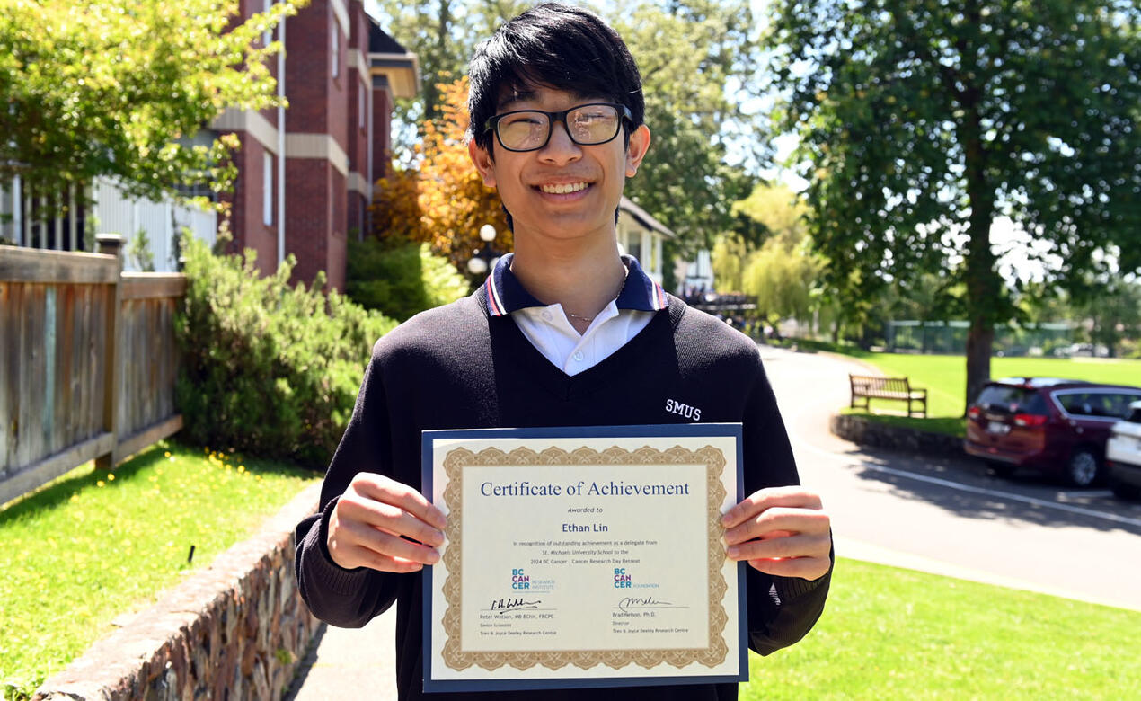Ethan Lin stands with certificate of achievement