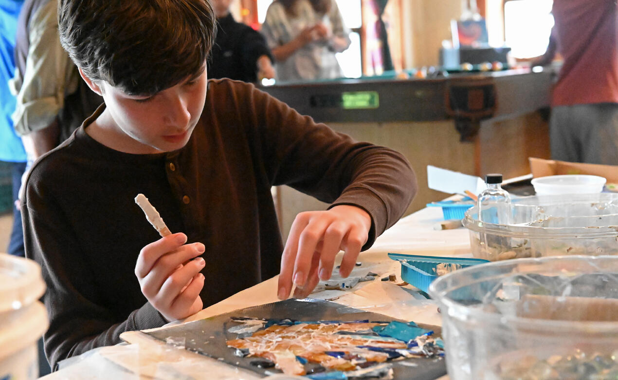 A student places pieces of tile onto a mosaic design