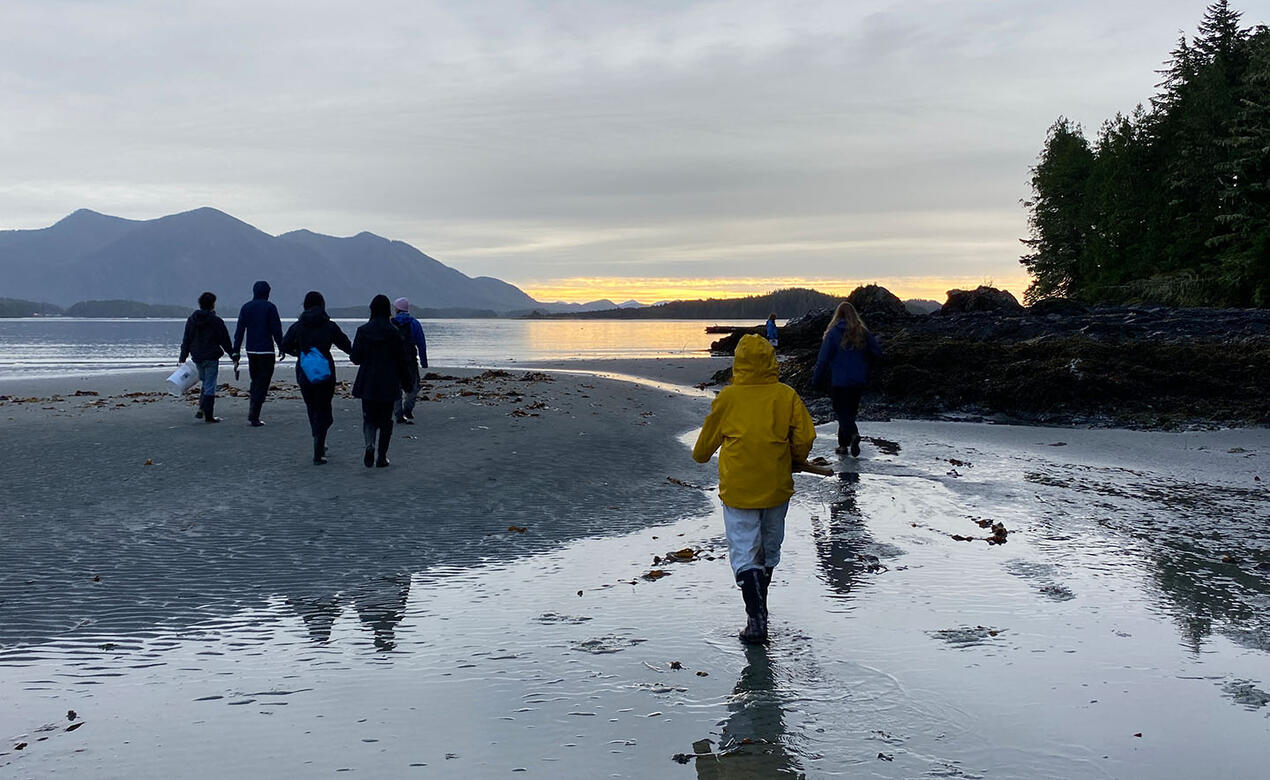Grade 12 Environmental Science students walk on beach at sunset