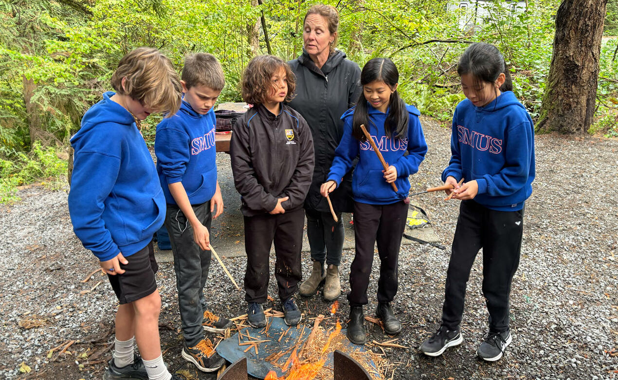 Grade 5 students stand beside fire at Goldstream Provincial Park