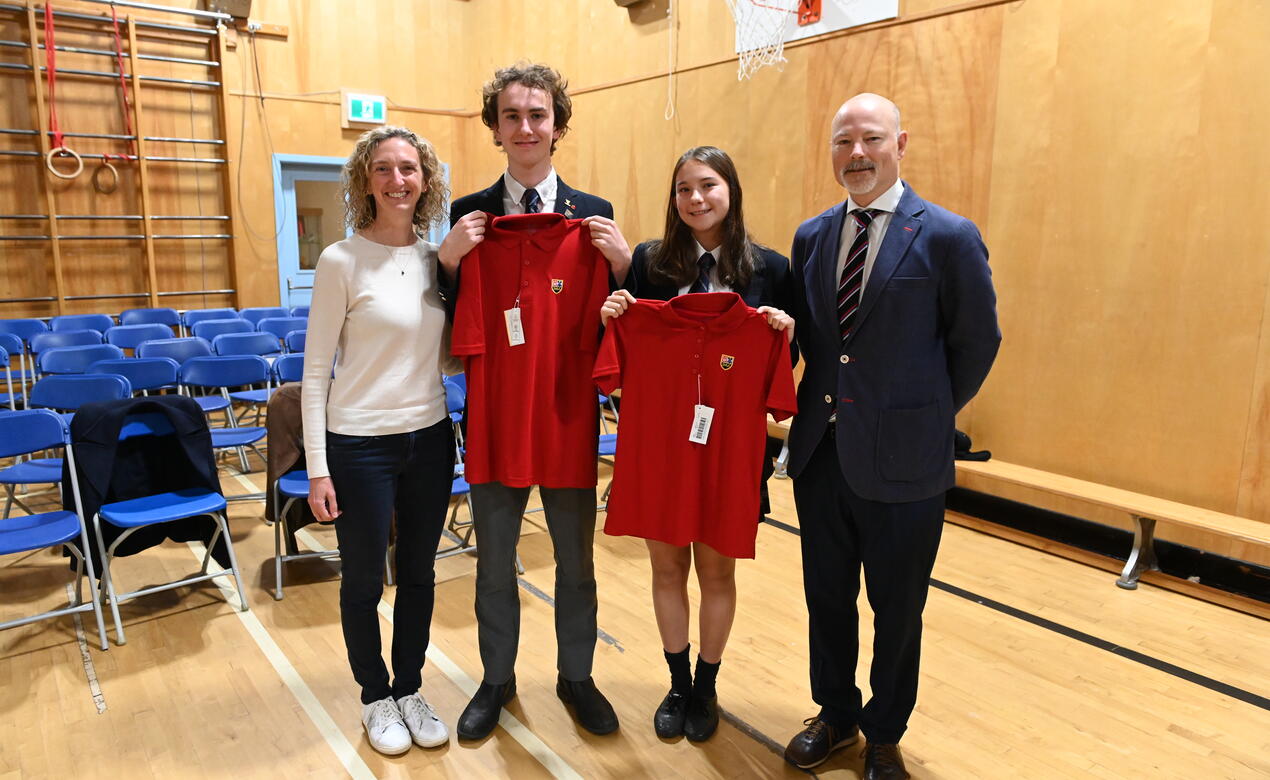 Lifers Will Cuddihy and Avery Geddes each stand with their parent, also Lifers of SMUS, at Lifer Assembly.