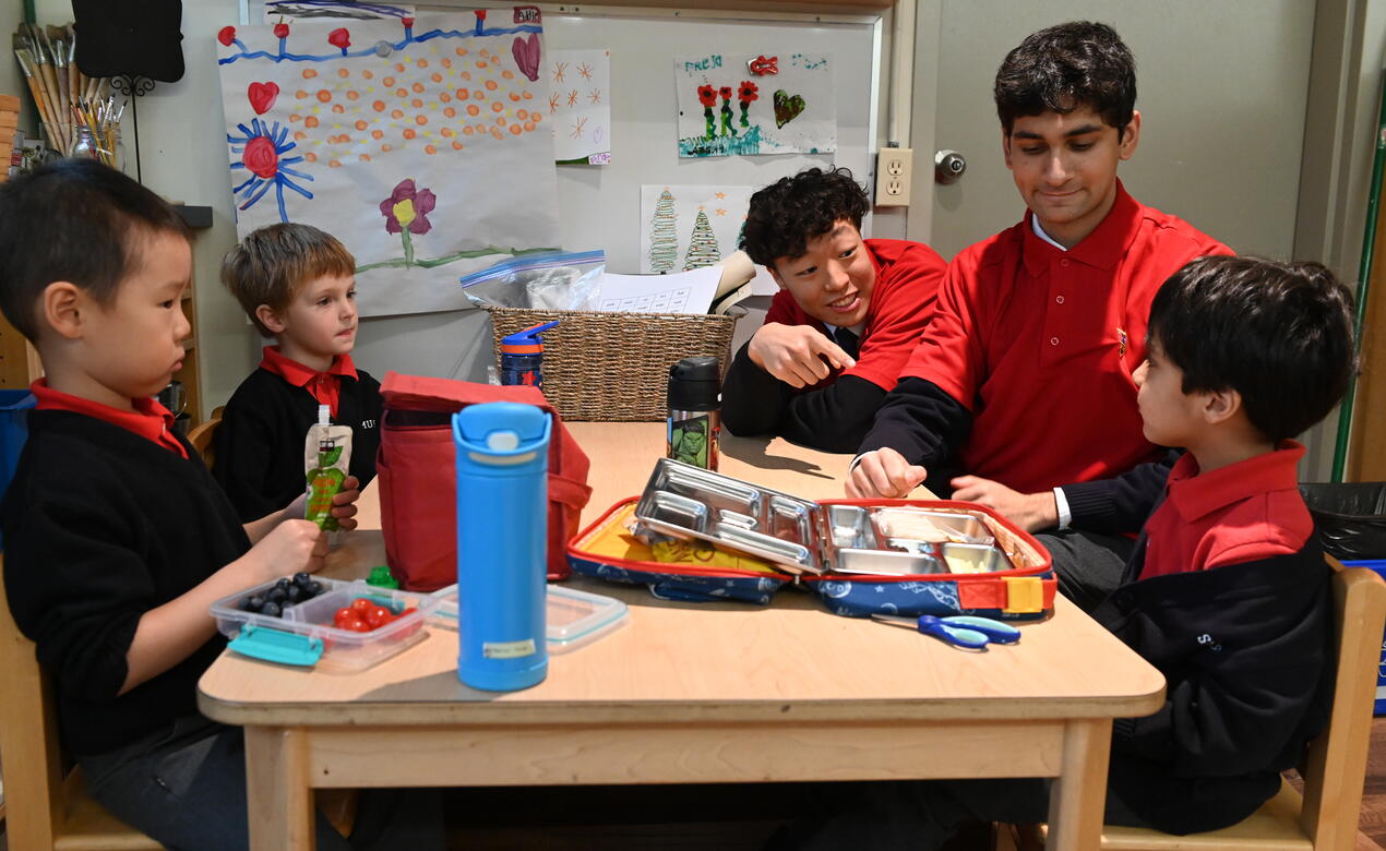 Two Lifers sit with current Kindergarten students during snack time