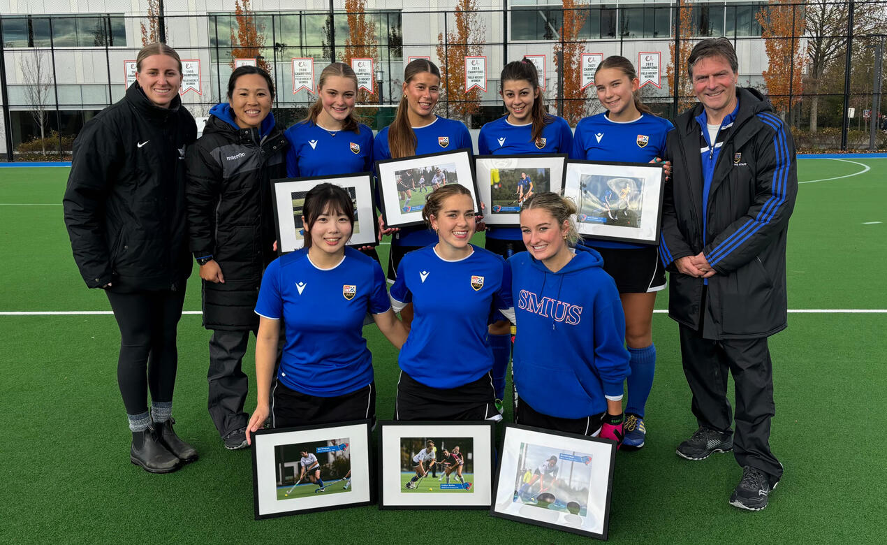 Seven graduating players hold their framed photos alongside proud coaches