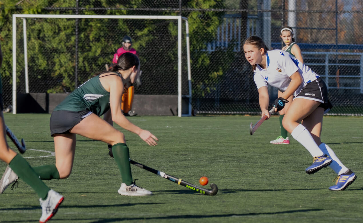 A SMUS player passes the ball over an opposing player's stick