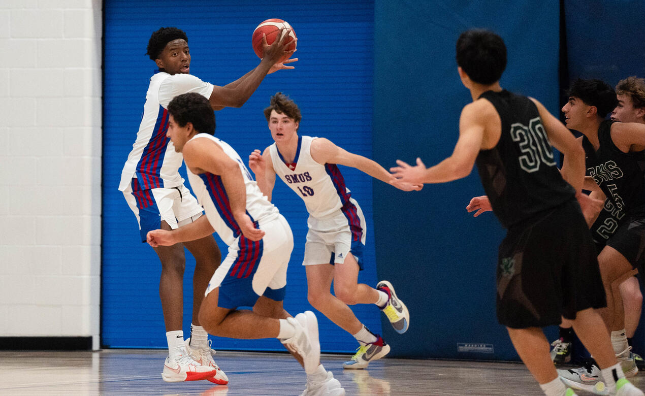 A player intercepts the ball as him teammates head up court