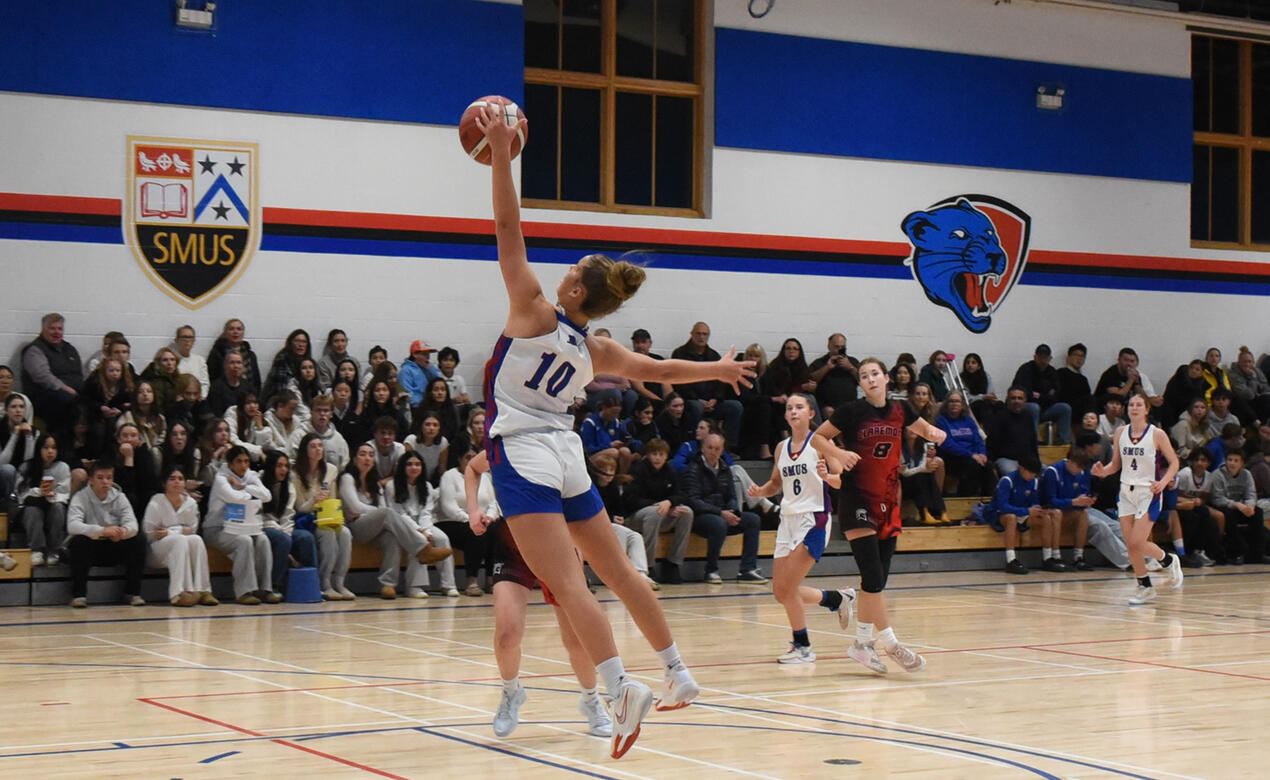 A SMUS basketball player leaps high to secure the ball